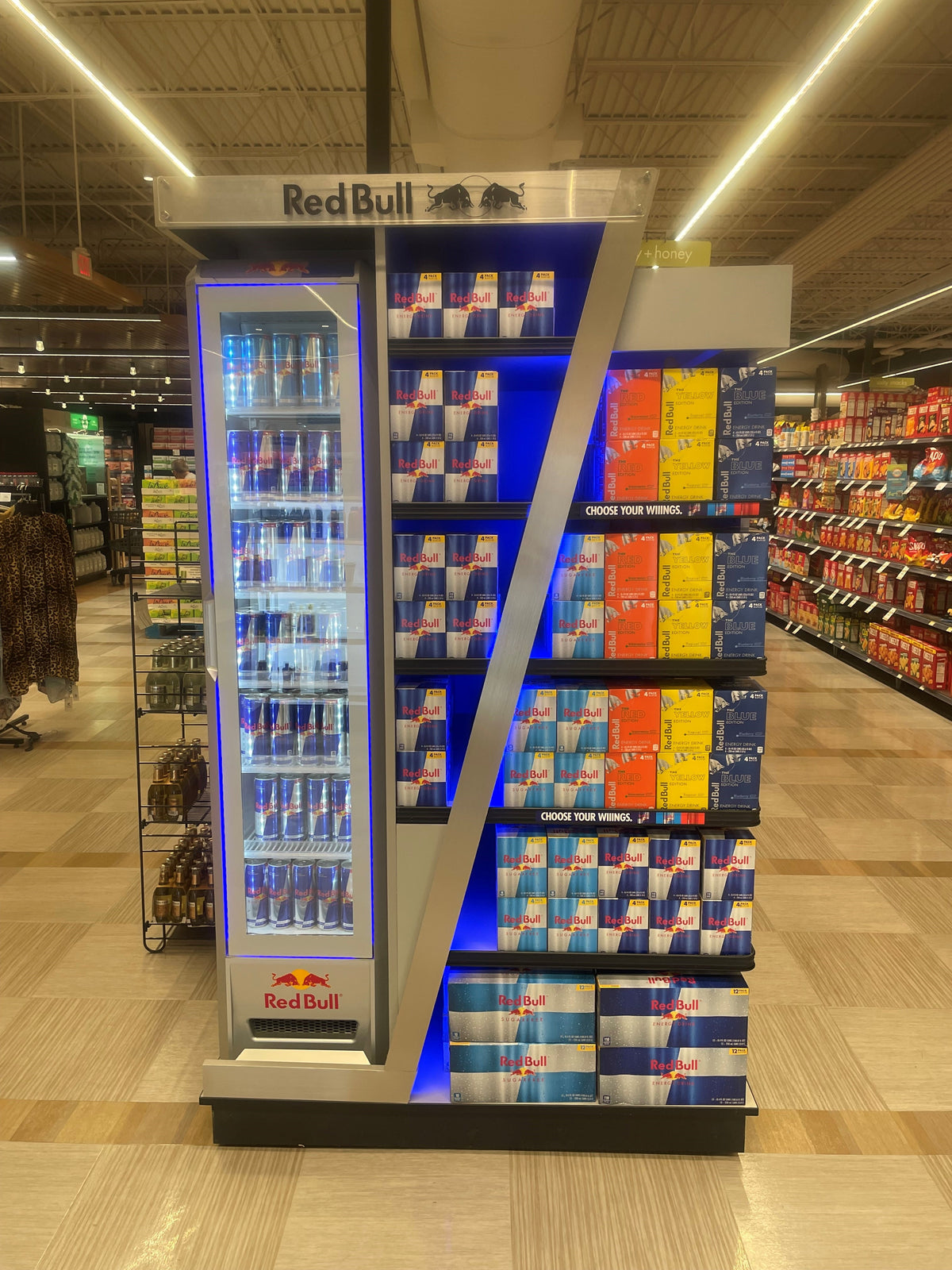 Red Bull End Cap display cooler in a store with various products on shelves.