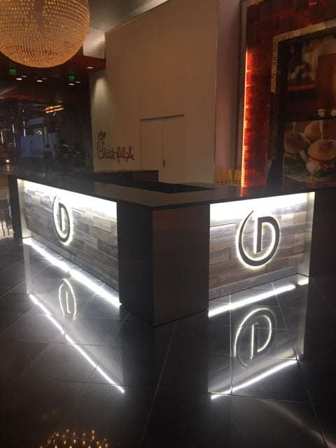 Modern reception desk with illuminated logo in a dimly lit room