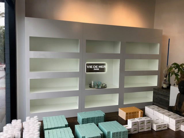 Display case with shelves and a 'Vie de Mer' sign, surrounded by crates and boxes.